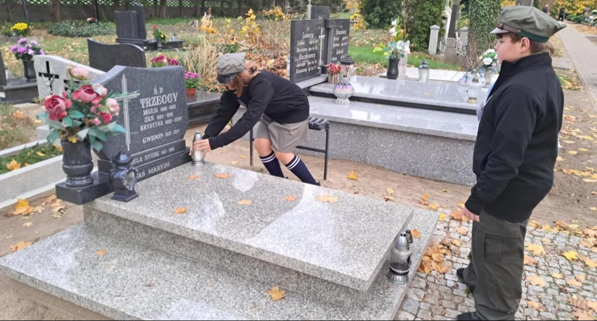 Harcerze Magdalena Błaszczak i Oskar Stachurski zapalają znicz na grobie, w którym spoczywa hm. Gwidon Trzecki fot. Magdalena Lachowicz