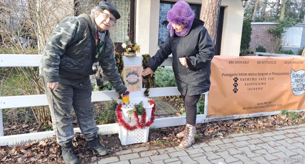 Irena Wojciechowska i Ewa Rembikowska pokazują zamontowaną skrzynkę, do której chętni mogą wkładać puszki z karmą dla kotów fot. Magdalena Lachowicz